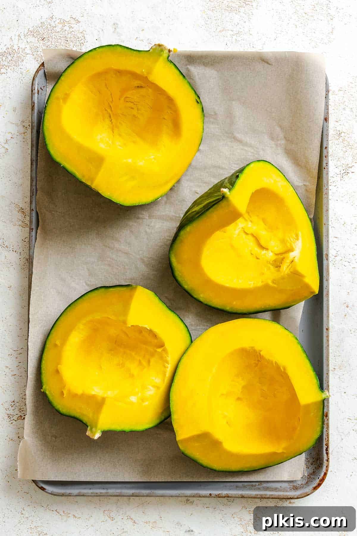 Velvety Golden Kabocha Soup 4 Process shot showing raw, quartered Kabocha Squash and onion pieces arranged on a baking tray, ready for roasting.