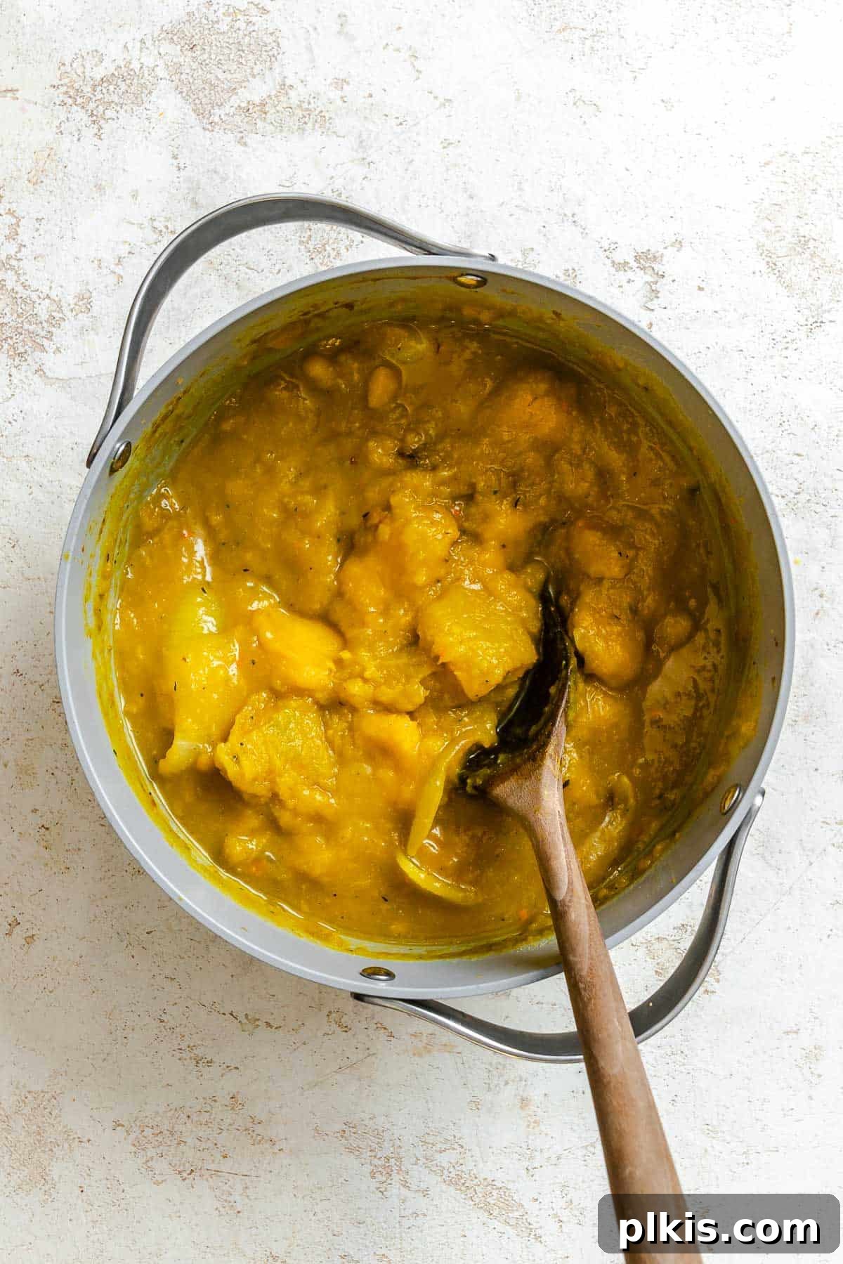 Velvety Golden Kabocha Soup 7 Process shot showing ingredients being stirred in a pot, simmering gently on a stovetop, with steam rising.