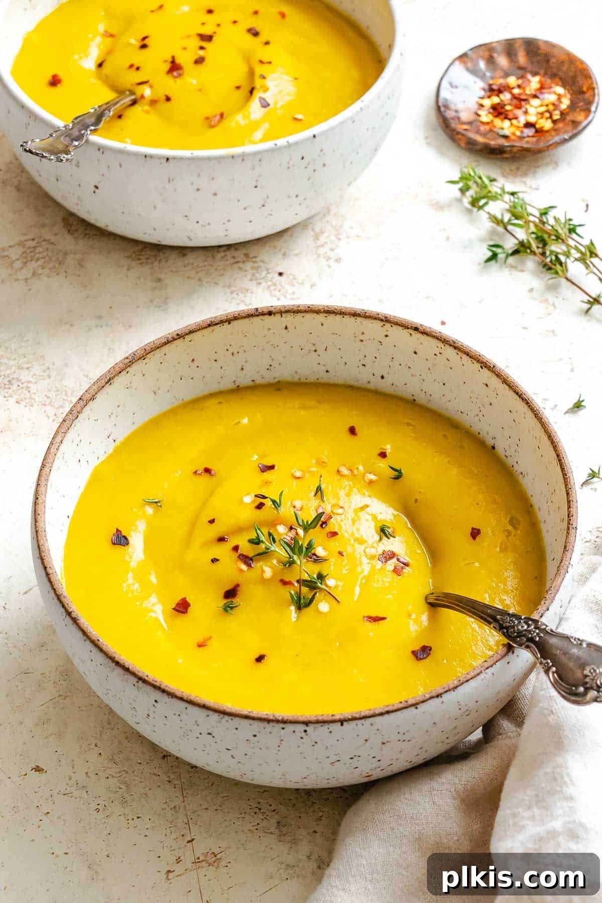 Velvety Golden Kabocha Soup 9 A bowl of creamy Kabocha Squash Soup, garnished with fresh herbs and a swirl of coconut cream, presented beautifully on a wooden surface, ready to be enjoyed.