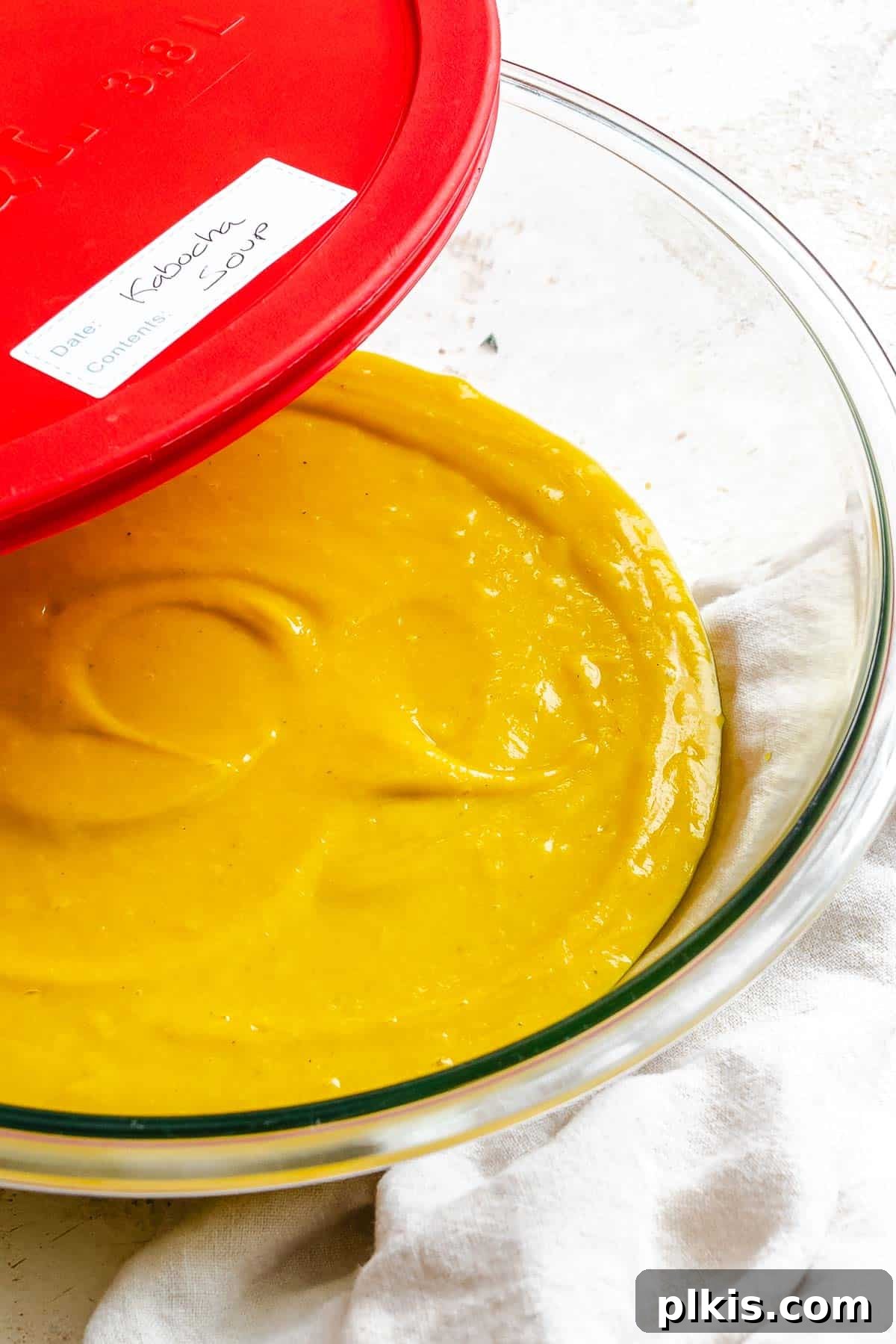 Velvety Golden Kabocha Soup 10 Kabocha Squash Soup stored in a transparent, airtight container, ready for refrigeration or freezing, emphasizing its convenience for meal prep.