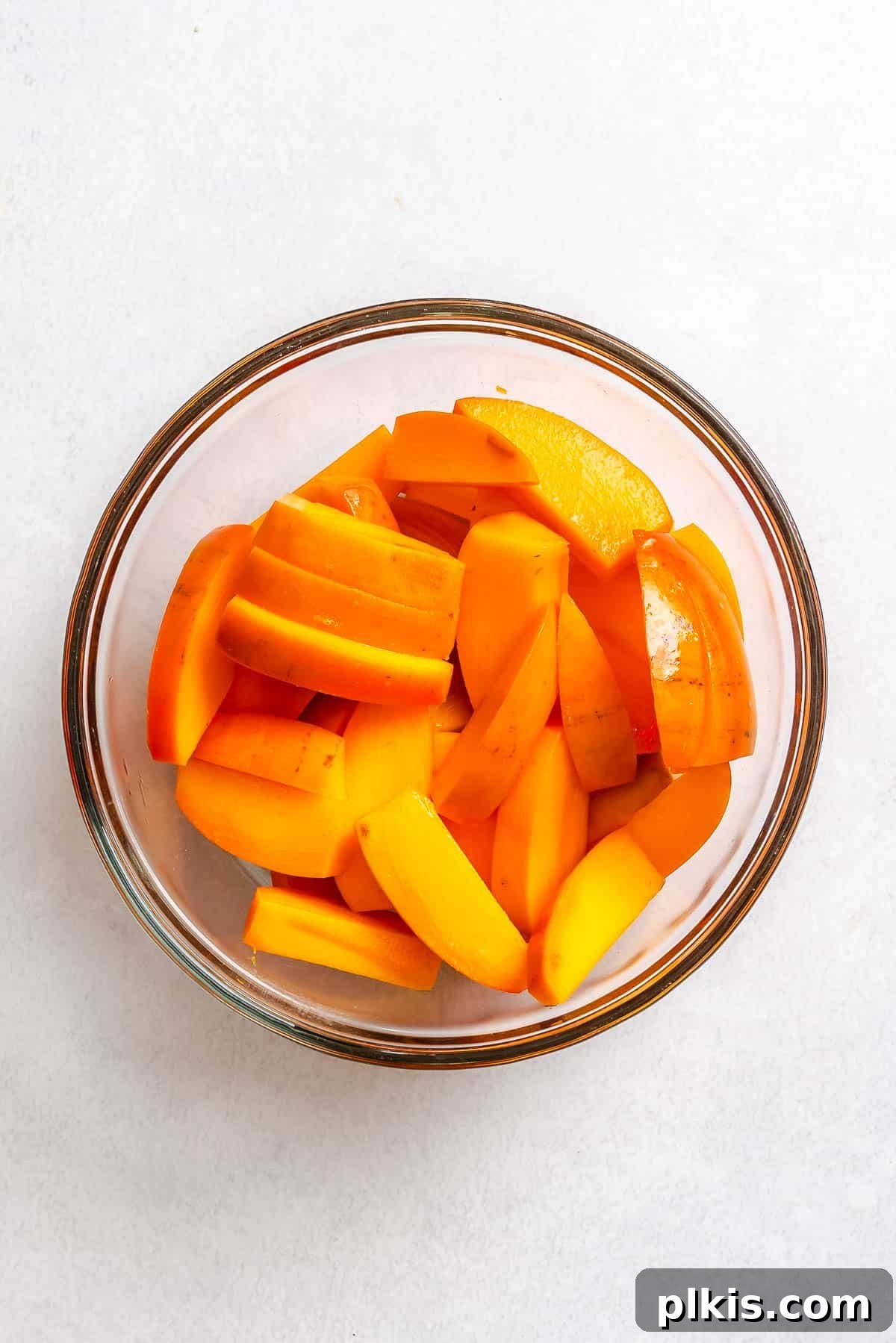 Golden Harvest Persimmon Salad 5 Process shot showing persimmons sliced in a bowl.