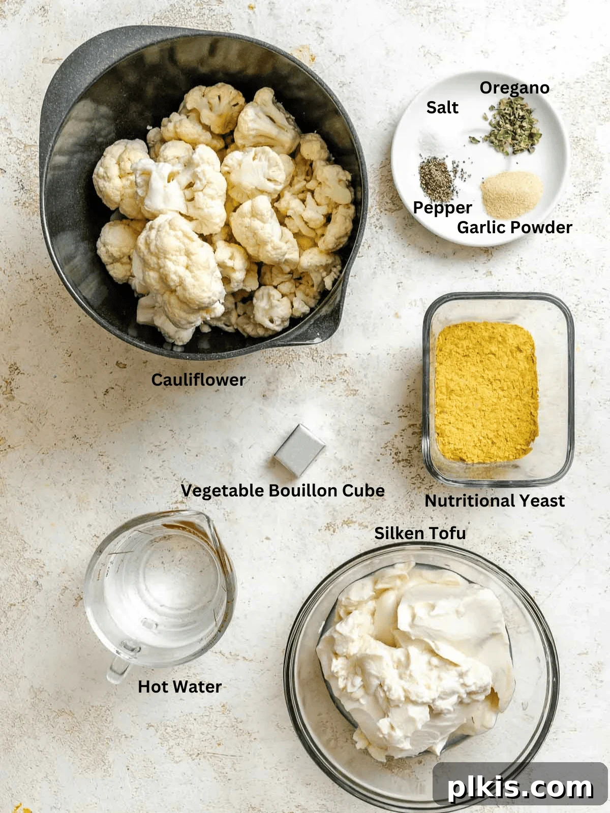 Creamy Vegan Cauliflower Alfredo Sauce Recipe 3 Ingredients for Cauliflower Alfredo Sauce (Vegan) measured out on a white surface.
