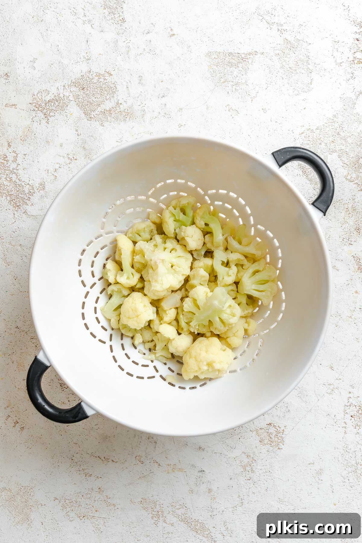 Creamy Vegan Cauliflower Alfredo Sauce Recipe 4 Process shot showing straining cauliflower in strainer.