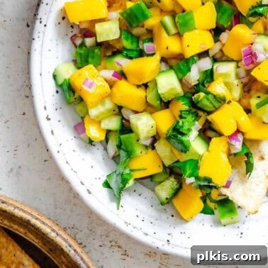 Fresh Strawberry Salsa: Sweet, Tangy Summer Recipe 10 Completed Mango Cucumber Salsa on a plate against a white surface.