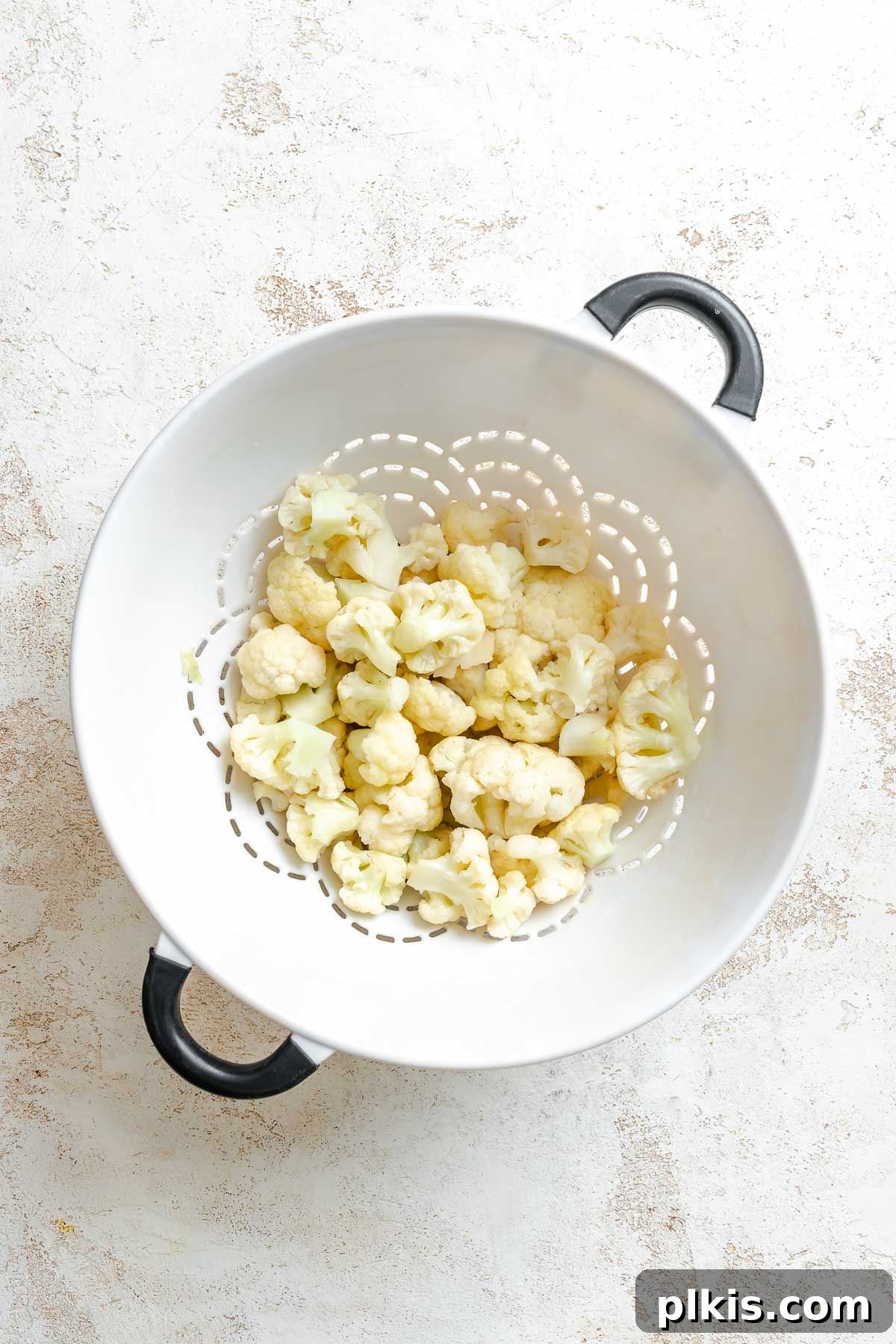 Roasted Cauliflower Salad with Lemon & Herbs 3 Process shot showing straining cauliflower florets in a strainer.