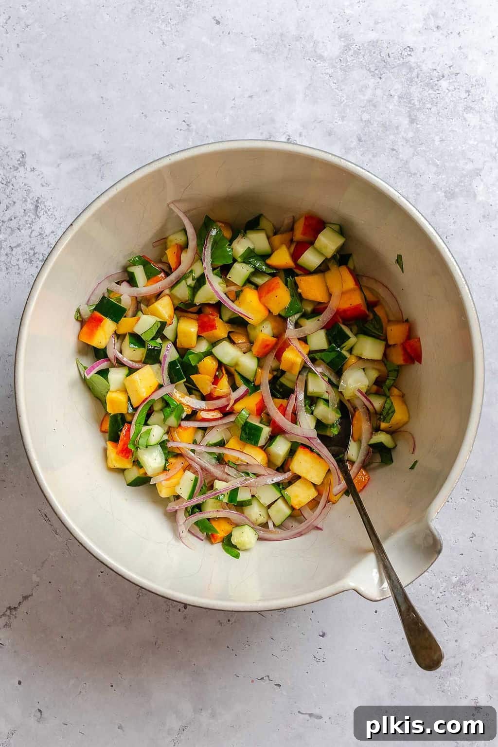 Cucumber and Peach Salad with Mint Lemon Vinaigrette 7 Process shot showing stirring ingredients in a bowl.