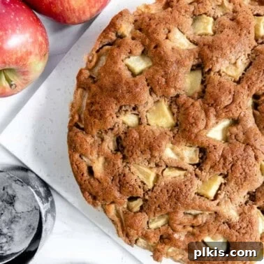 finished apple cake with two apples and measuring tools against a white background