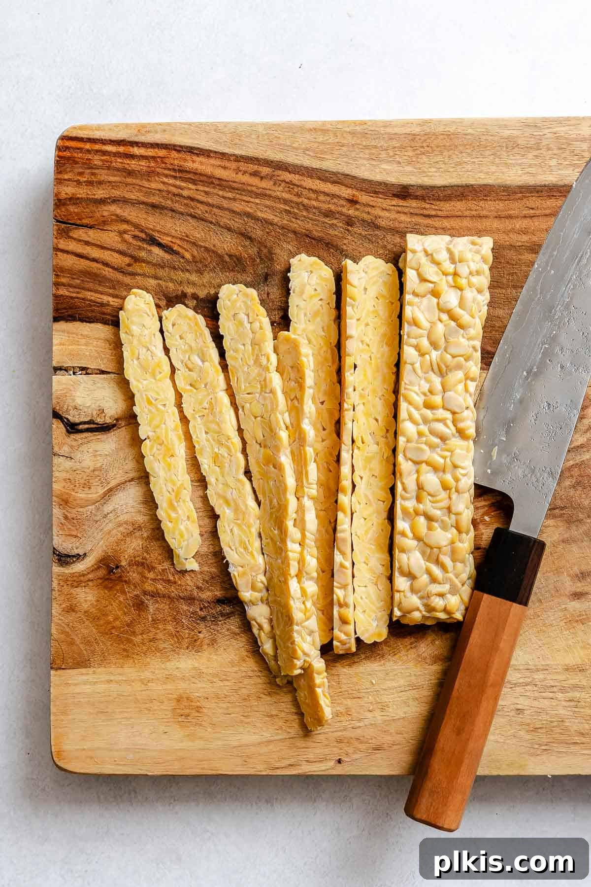 Slicing tempeh on a cutting board.
