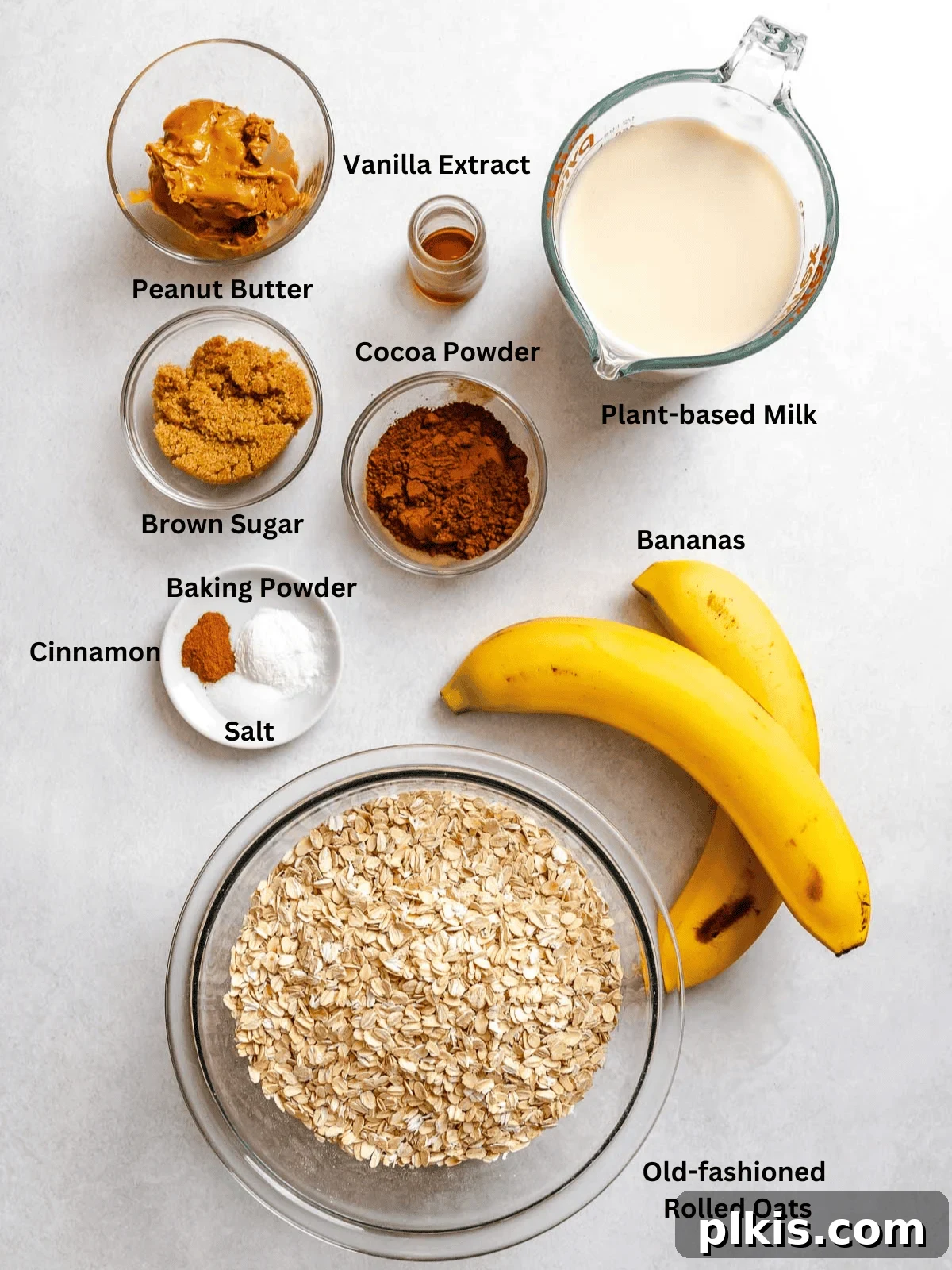 Chocolate Banana Baked Oatmeal with Peanut Butter Swirl 3 Ingredients for Chocolate Banana Baked Oatmeal (with peanut butter) measured out on a white surface.