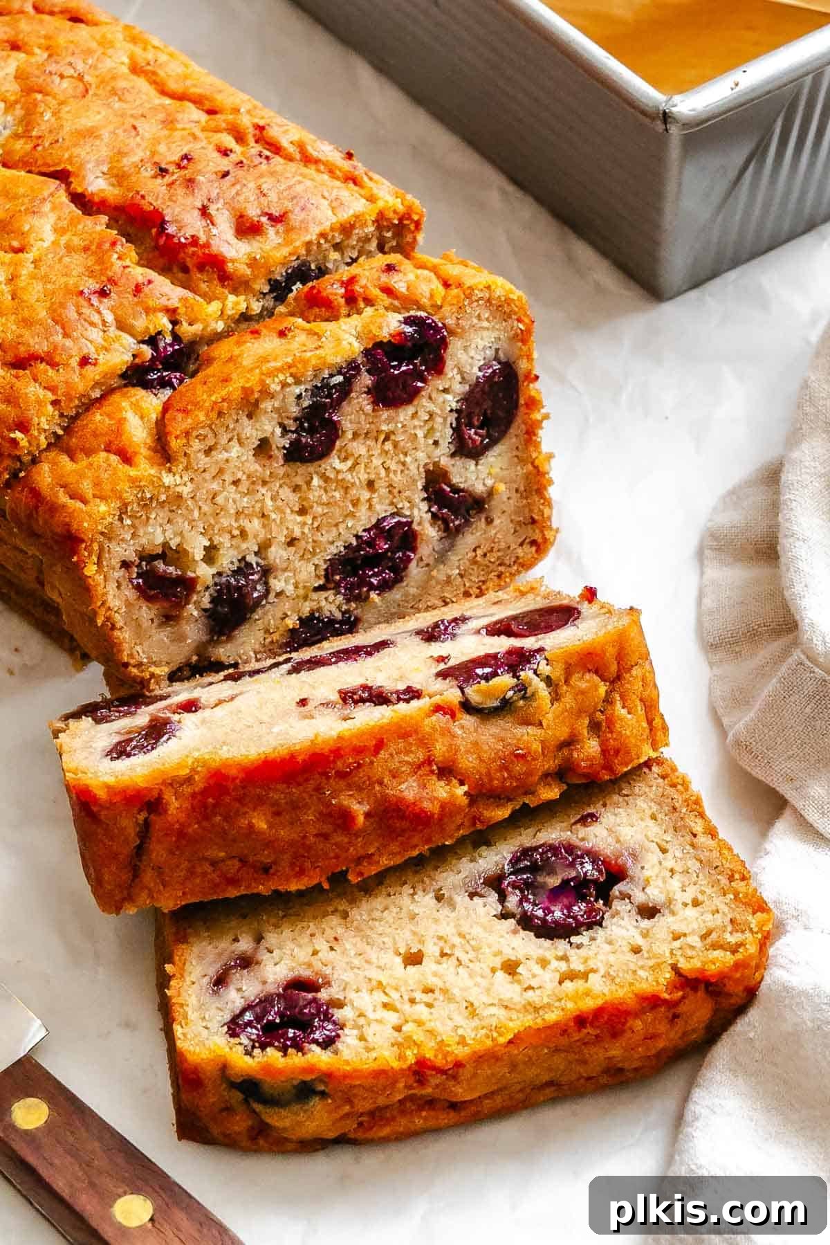 Eggless Cranberry Orange Bread Recipe 2 Completed Cranberry Orange Bread (Eggless!) sliced on white surface.